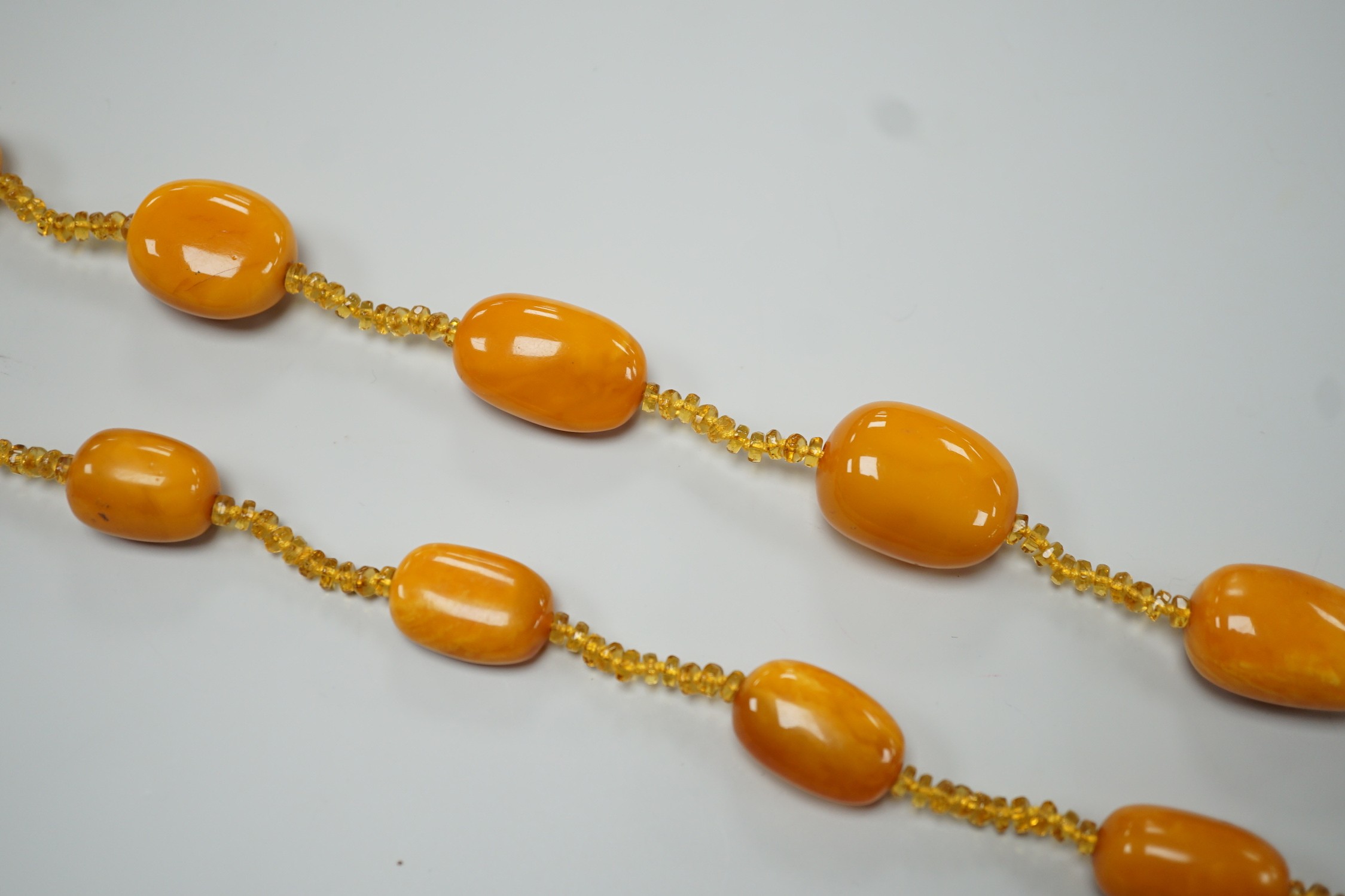 A single strand graduated fifteen amber bead necklace, with multiple amber? spacers, 84cm, gross weight 89 grams.